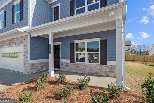 property entrance featuring a porch, a garage, and a lawn