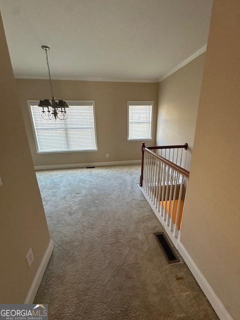 interior space with an inviting chandelier, carpet, and crown molding