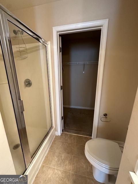 bathroom featuring toilet, tile patterned flooring, and an enclosed shower