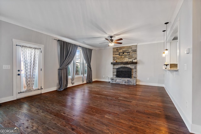 unfurnished living room featuring crown molding, ceiling fan, dark wood-type flooring, and a stone fireplace