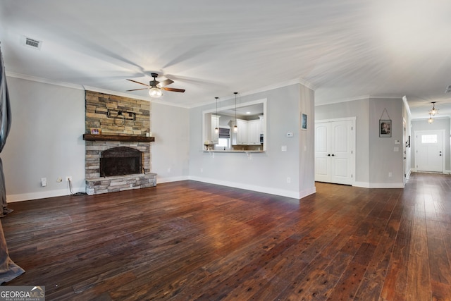 unfurnished living room featuring dark hardwood / wood-style floors, a stone fireplace, ceiling fan, and crown molding