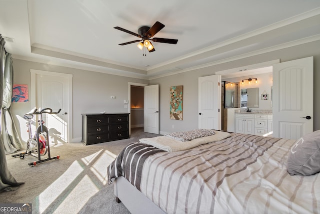 bedroom with ceiling fan, a raised ceiling, light carpet, and ensuite bath