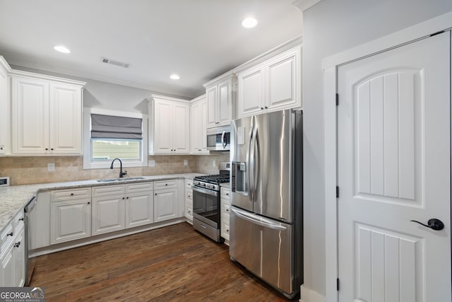 kitchen featuring sink, dark wood-type flooring, light stone counters, white cabinets, and appliances with stainless steel finishes