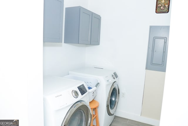 laundry area with electric panel, cabinets, light hardwood / wood-style floors, and independent washer and dryer