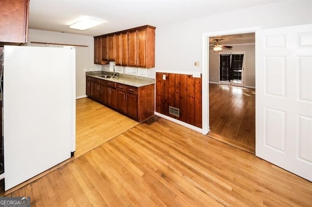 kitchen with ceiling fan, white fridge, sink, and light hardwood / wood-style flooring