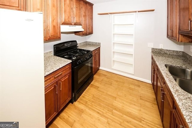 kitchen with black gas stove, white refrigerator, light hardwood / wood-style flooring, and light stone counters