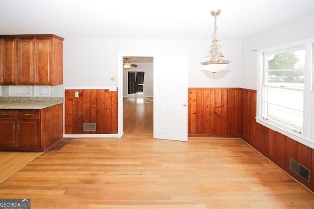 unfurnished dining area with light wood-type flooring and ceiling fan