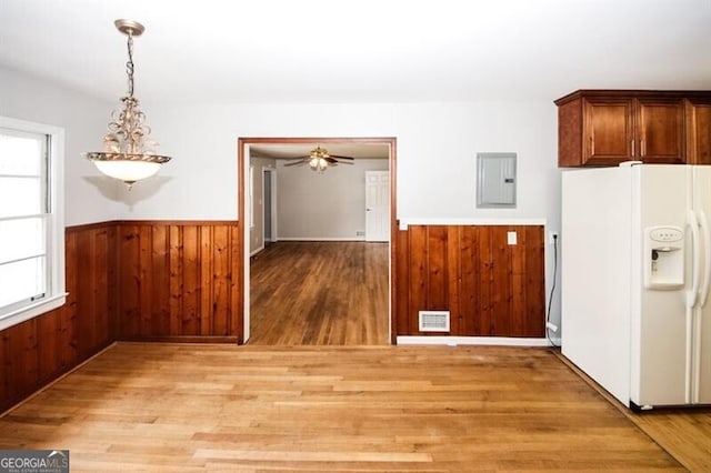 unfurnished dining area featuring electric panel, light hardwood / wood-style flooring, and a healthy amount of sunlight