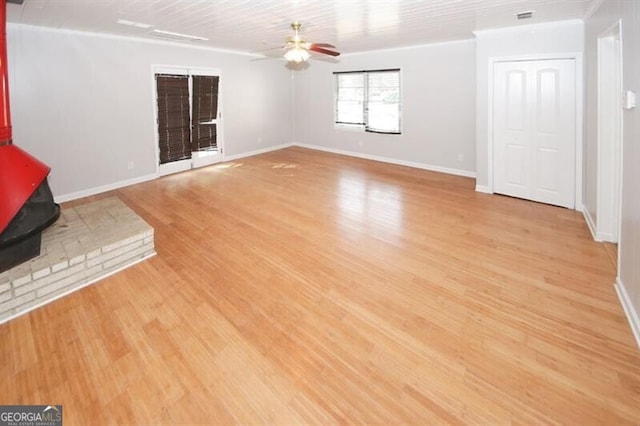 unfurnished living room featuring a wood stove, ceiling fan, and light hardwood / wood-style flooring