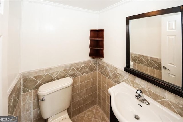 bathroom with crown molding, sink, tile walls, and toilet