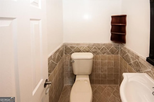 bathroom featuring toilet and tile walls