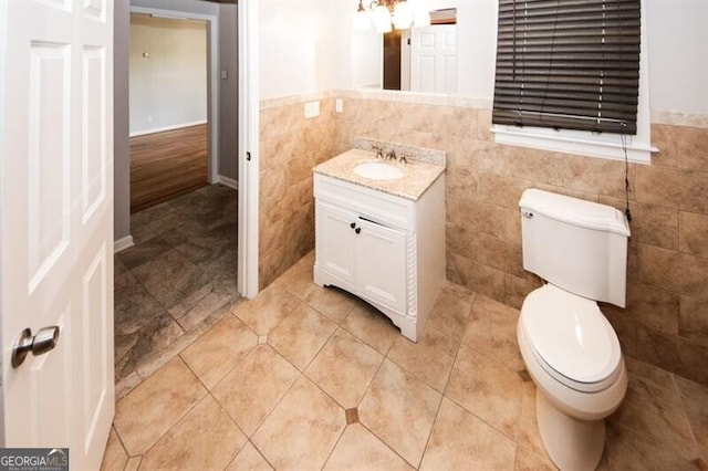 bathroom with tile patterned floors, vanity, toilet, and tile walls