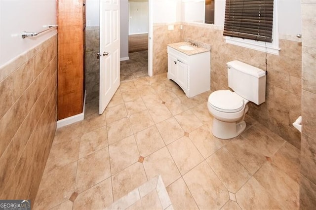 bathroom featuring tile patterned flooring, vanity, tile walls, and toilet