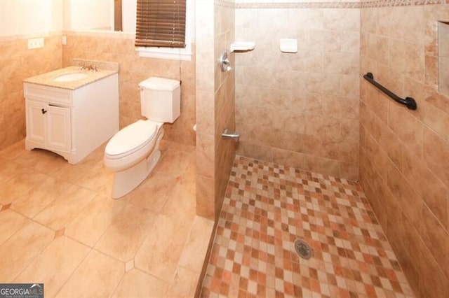 bathroom featuring a tile shower, vanity, tile walls, and toilet