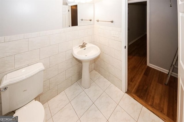 bathroom featuring wood-type flooring, tile walls, and toilet