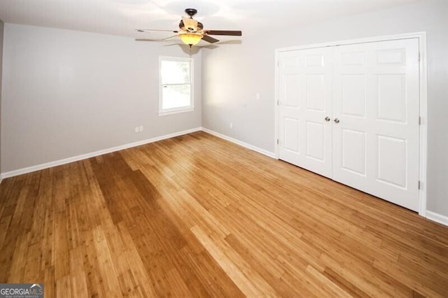 unfurnished bedroom with hardwood / wood-style flooring, ceiling fan, and a closet