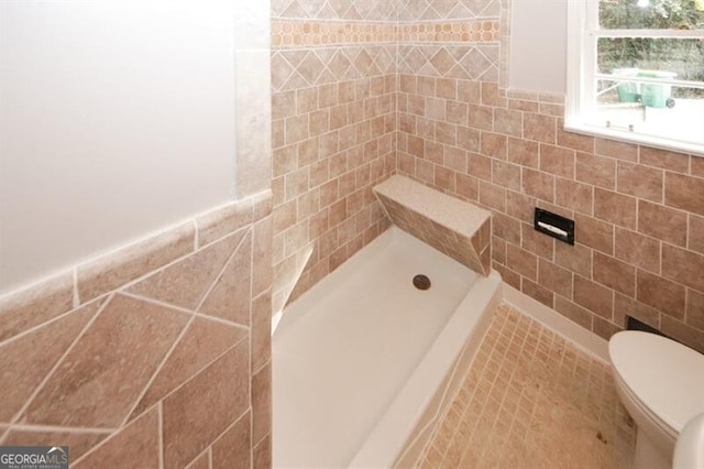 bathroom featuring a tile shower, tile walls, and toilet