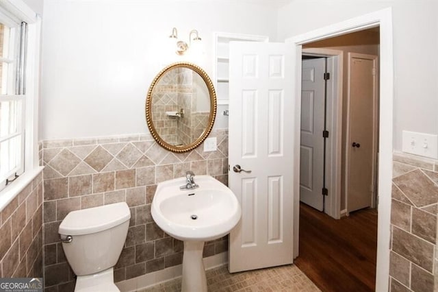 bathroom featuring toilet, wood-type flooring, and tile walls