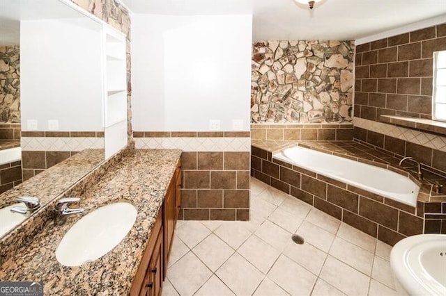 bathroom with tile patterned flooring, vanity, tile walls, and tiled tub