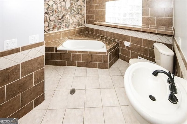 bathroom featuring tiled bath, tile patterned floors, tile walls, and sink