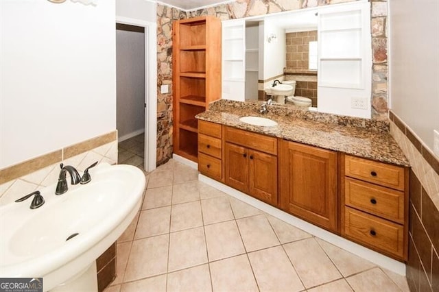 bathroom with toilet, tile patterned floors, tile walls, and sink