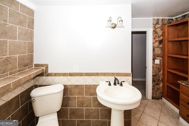 bathroom with tile patterned flooring, tile walls, and toilet