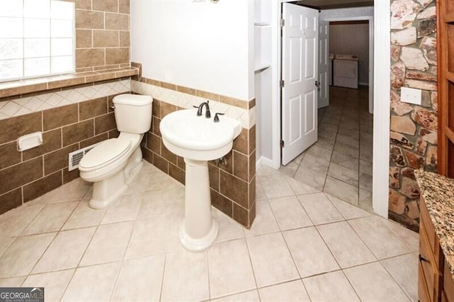 bathroom with tile patterned floors, toilet, and tile walls