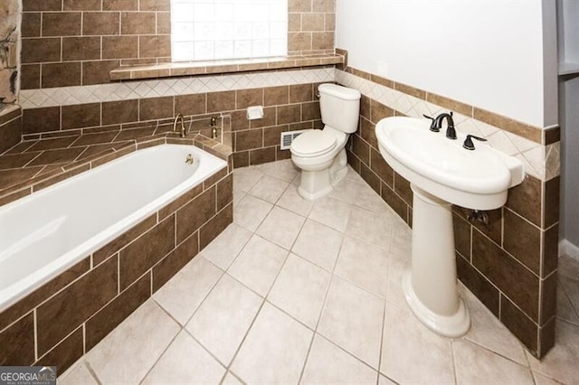 bathroom with tile patterned flooring, toilet, and tile walls