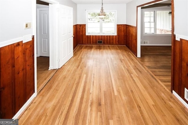 unfurnished dining area featuring wood walls and light hardwood / wood-style flooring