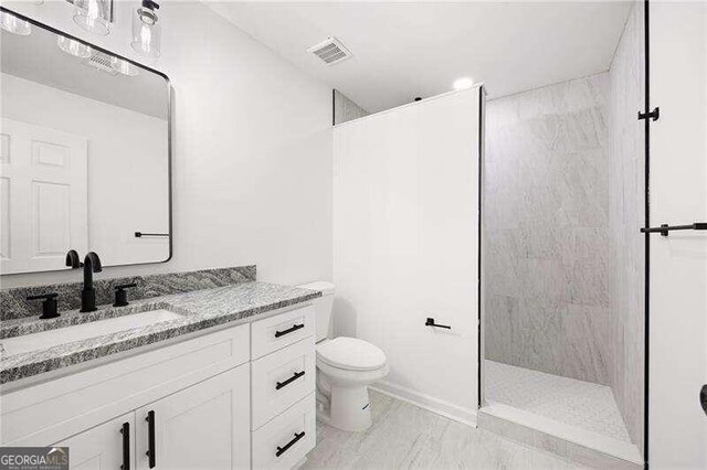 bathroom featuring vanity, toilet, and tiled shower