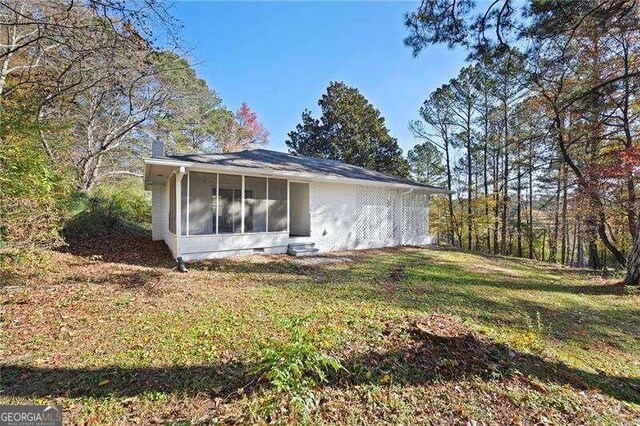 view of home's exterior with a sunroom and a yard