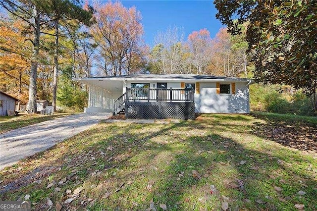 single story home with a carport, a front yard, and a wooden deck