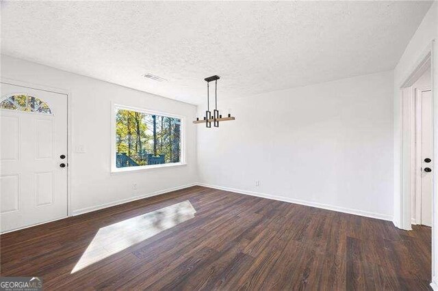 entrance foyer with dark hardwood / wood-style floors, a textured ceiling, and an inviting chandelier