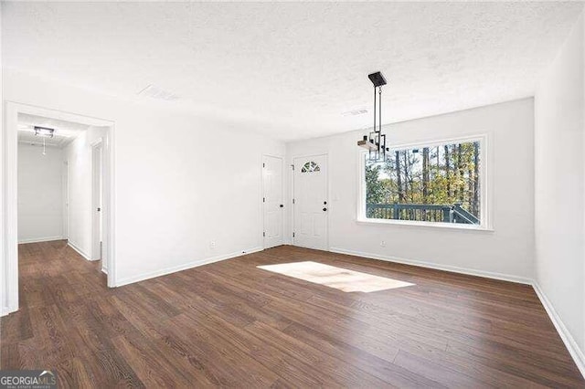 unfurnished room with a textured ceiling and dark hardwood / wood-style floors