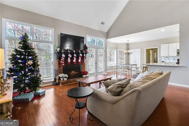 living room with sink, dark hardwood / wood-style flooring, high vaulted ceiling, a chandelier, and a fireplace