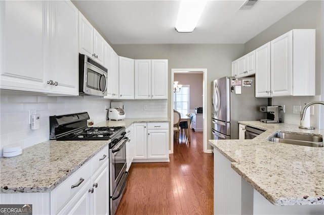 kitchen featuring white cabinetry, sink, light stone countertops, dark hardwood / wood-style floors, and appliances with stainless steel finishes