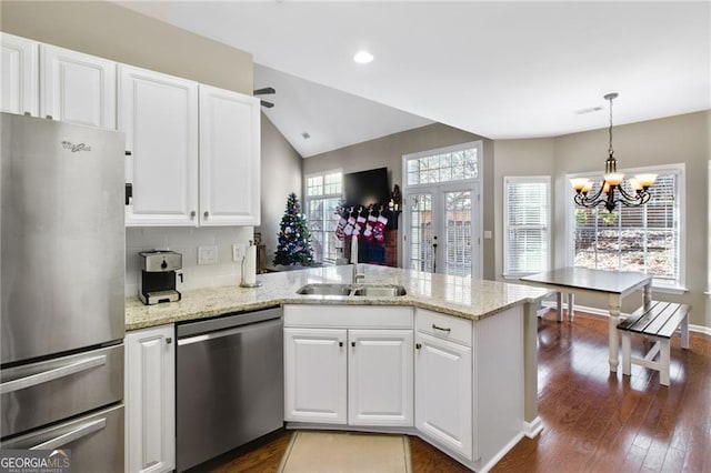 kitchen with kitchen peninsula, stainless steel appliances, sink, an inviting chandelier, and white cabinetry