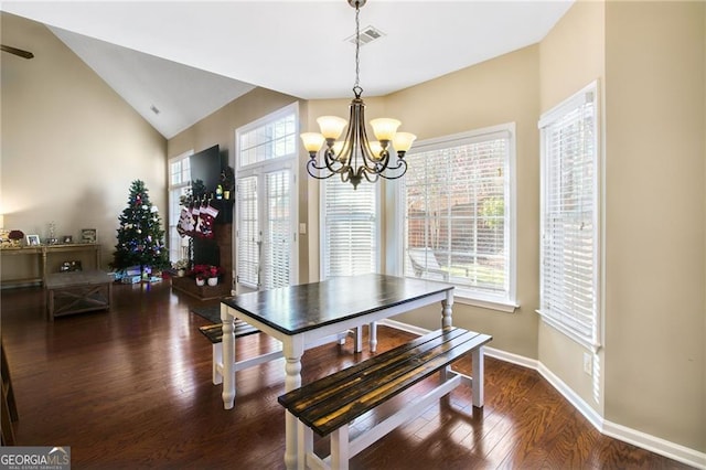 dining area with dark hardwood / wood-style flooring, lofted ceiling, and an inviting chandelier