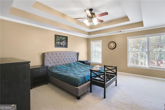 bedroom featuring a tray ceiling, multiple windows, ceiling fan, and light colored carpet