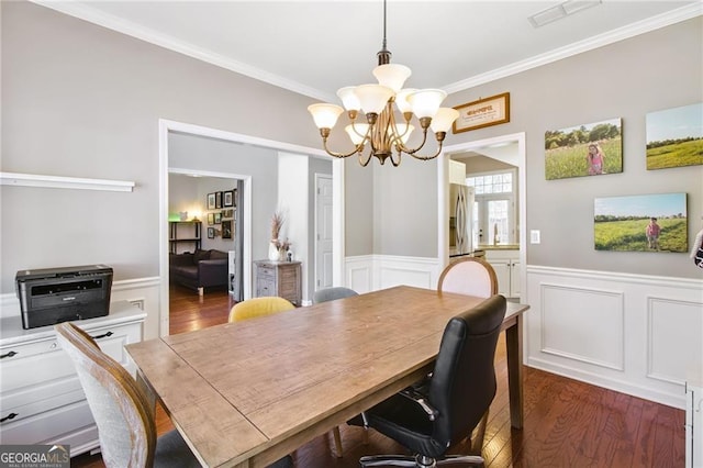 dining area featuring dark hardwood / wood-style flooring, ornamental molding, and a chandelier