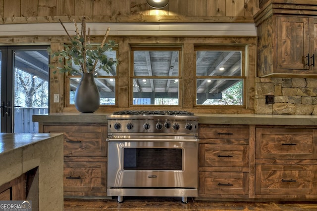 kitchen with wooden walls, dark hardwood / wood-style flooring, designer stove, and a healthy amount of sunlight