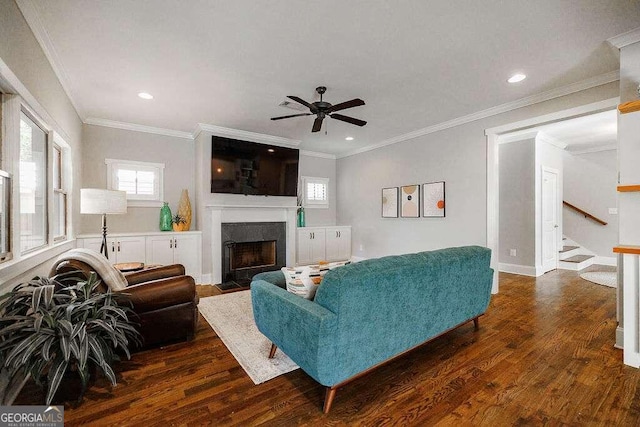 living room with ceiling fan, dark hardwood / wood-style flooring, ornamental molding, and a tile fireplace