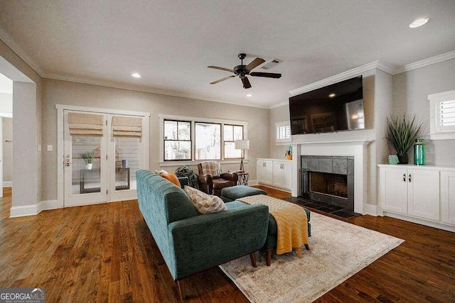 living room with dark wood-type flooring, a healthy amount of sunlight, and ornamental molding