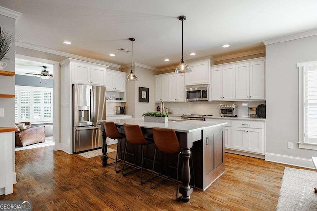 kitchen featuring appliances with stainless steel finishes, light hardwood / wood-style flooring, white cabinetry, and pendant lighting