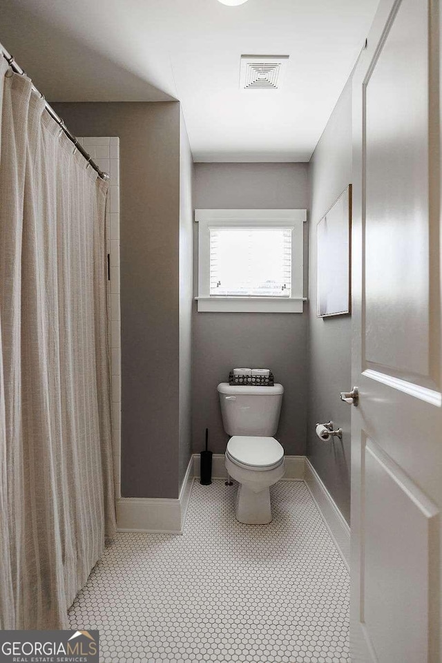 bathroom with tile patterned floors, a shower with curtain, and toilet