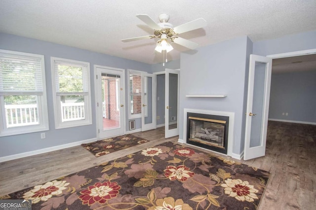 611 Bernhard Rd, Fayetteville, GA 30215 - unfurnished living room with wood finished floors, a glass covered fireplace, a textured ceiling, and a ceiling fan