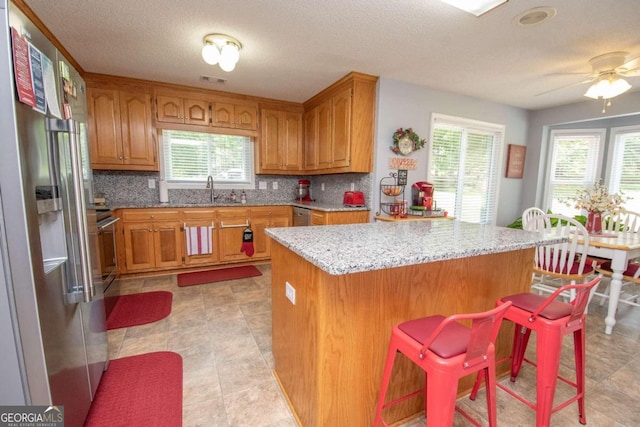 611 Bernhard Rd, Fayetteville, GA 30215 - kitchen featuring stainless steel refrigerator with ice dispenser, tasteful backsplash, brown cabinets, healthy amount of natural light, and a textured ceiling