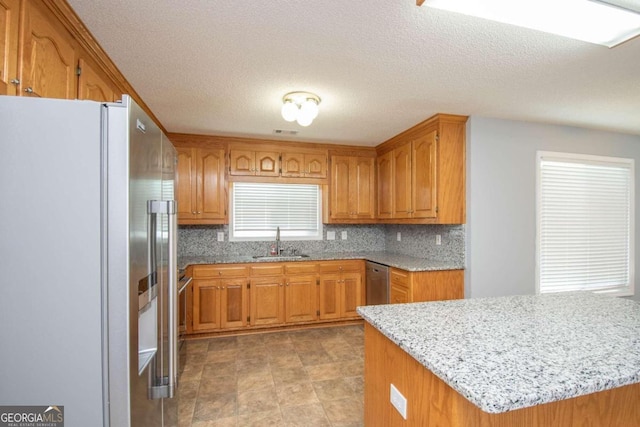 611 Bernhard Rd, Fayetteville, GA 30215 - kitchen featuring freestanding refrigerator, brown cabinets, tasteful backsplash, stainless steel dishwasher, and a textured ceiling