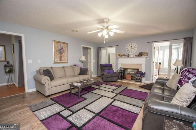 611 Bernhard Rd, Fayetteville, GA 30215 - living room featuring a ceiling fan, wood finished floors, a fireplace with raised hearth, and a textured ceiling