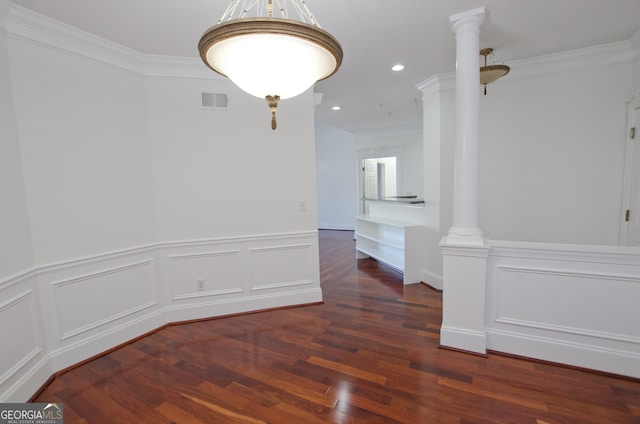 spare room featuring decorative columns, crown molding, and dark hardwood / wood-style floors